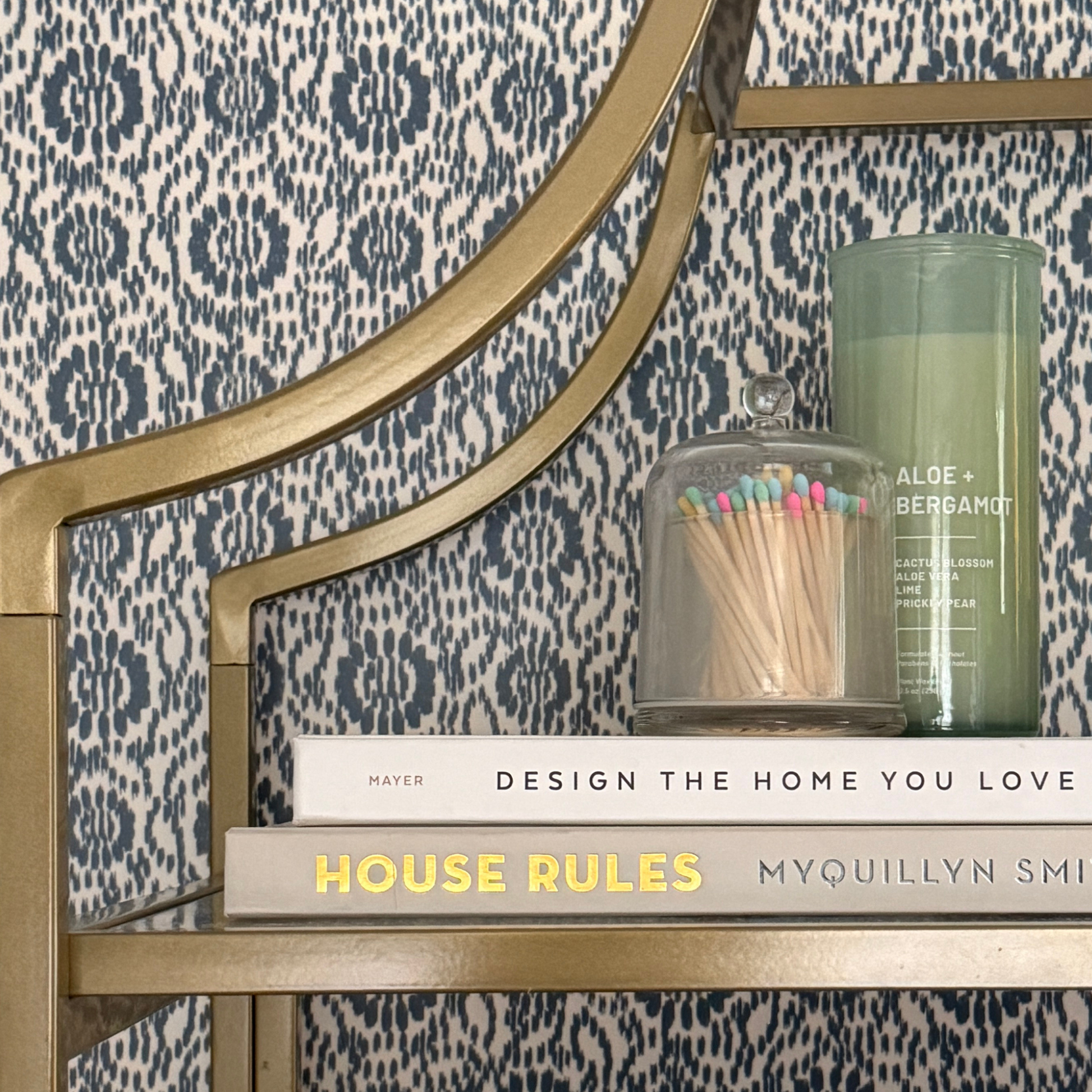 Indigo Threads wallpaper styled behind a gold shelf styled with books.